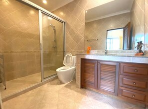Un baño moderno con ducha acristalada, inodoro y muebles de madera.