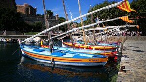 A row of colorful boats docked at a harbor with a stone wall and a building in the background.