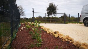 A gravel driveway leading to a gated entrance with a vehicle parked nearby.