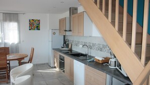 A modern kitchen with wooden cabinets, a dishwasher, a sink, and a dining area with a table and chairs.