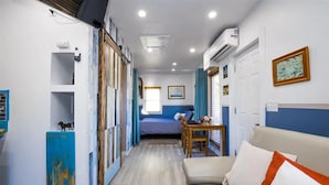 Un pasillo estrecho con una cama, un sofá y una mesa en la habitación.