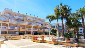 A multi-story hotel with balconies, outdoor seating, and palm trees. - Apartament Playa Sol by DENIA COSTA (Denia)