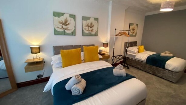 Une chambre d’hôtel avec un lit, deux tables de chevet, un miroir et des œuvres d’art accrochées aux murs.
