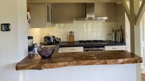 Una cocina con encimera de madera, estufa a gas, armarios blancos y salpicadero de azulejos.