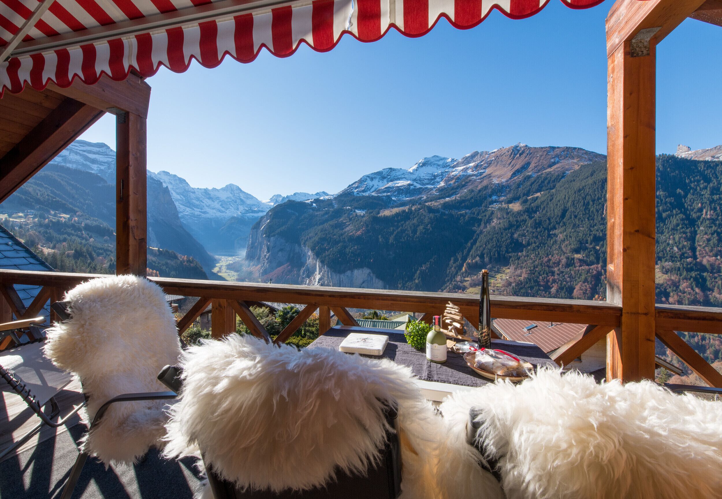 A wooden deck with a red and white striped awning overlooking a mountainous landscape.