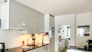 A modern kitchen with white cabinets, a black countertop, and stainless steel appliances.