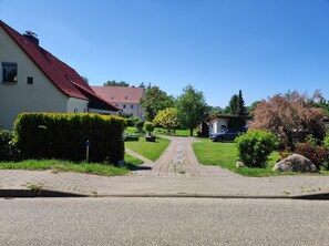 Eine Wohnstraße mit Häusern, einer gepflasterten Auffahrt und einem parkenden Auto am Straßenrand.