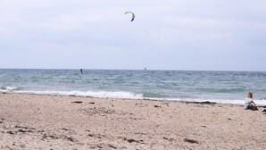 A beach with a person flying a kite and another person sitting on the sand. - 2 bedroom apartment in neuburg steinhausen (Neuburg Steinhausen)