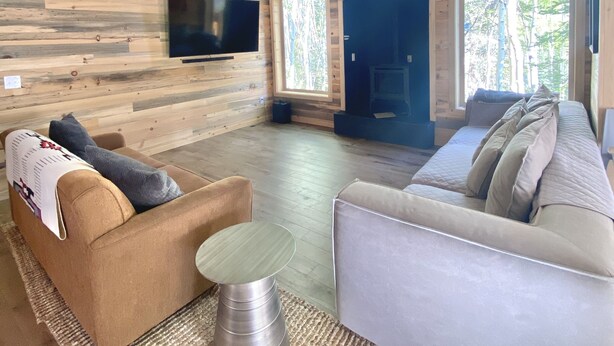 Un salón amplio con techo alto, paredes de madera y ventanas grandes que ofrecen vistas al exterior.