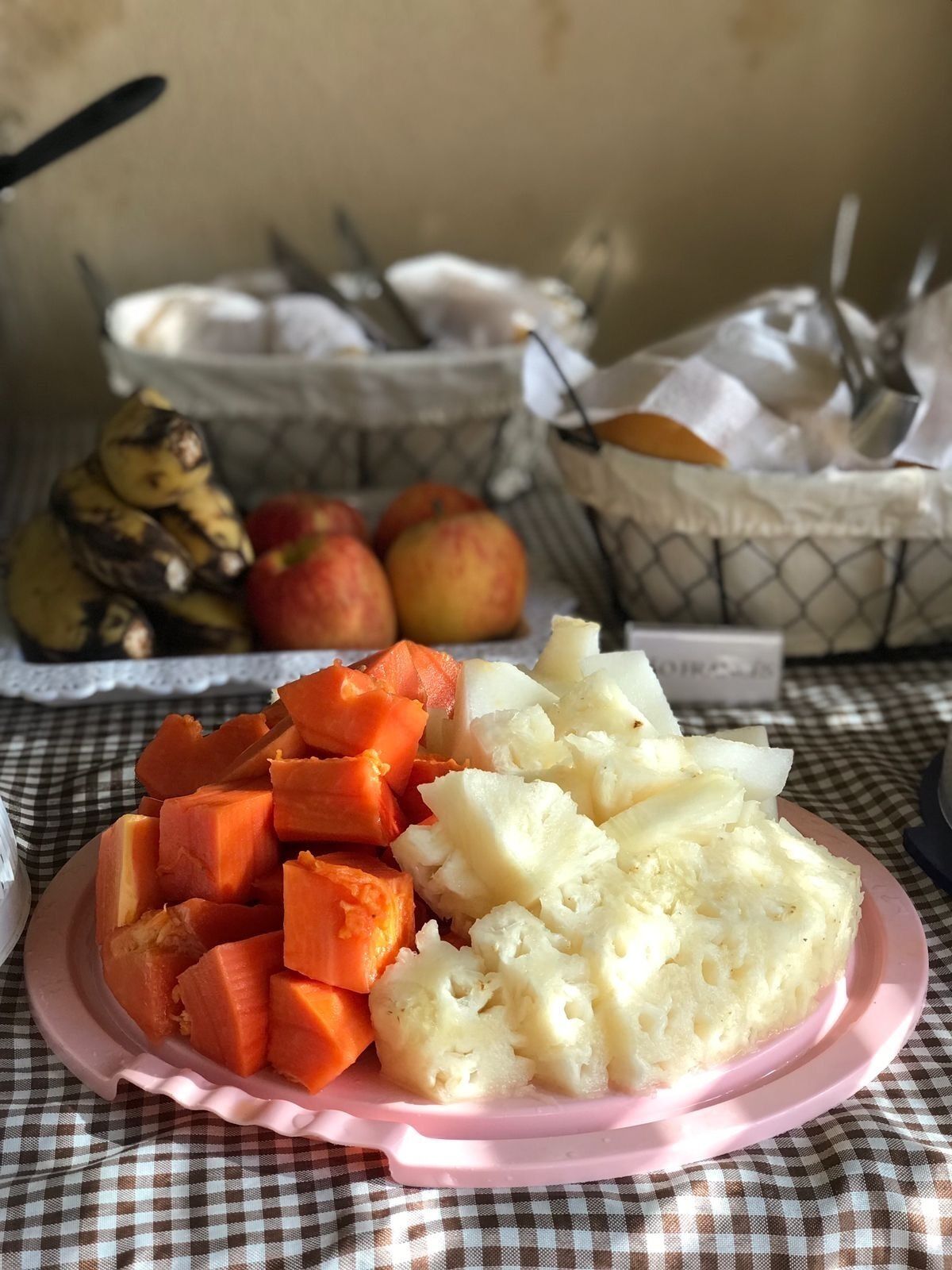 A plate of sliced carrots and potatoes on a checkered tablecloth.