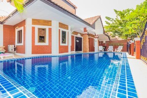 Ein Wohnhaus mit Schwimmbad, überdachter Terrasse und Ziegelaußenwand.