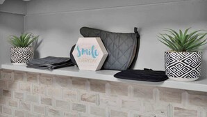 Een plank met twee planten in potten, een opgevouwen handdoek en een zeshoekig bordje met de tekst 'Smile Everyday'.
