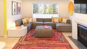 A modern living room with a sectional sofa, a colorful rug, and a fireplace. - ⟰ DELIGHTFULLY DESIGNED (Boyne City)