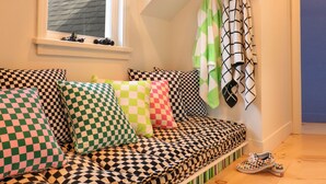 A cozy loft bedroom with a checkered sofa, hanging plants, and a view of the sky through a window. - ⟰ DELIGHTFULLY DESIGNED (Boyne City)