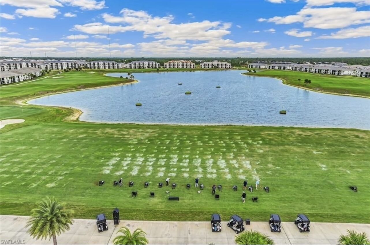 Un campo de golf con un gran estanque, rodeado de edificios.
