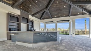 A spacious outdoor area with a modern bar and seating area, featuring a high ceiling and large windows overlooking a scenic view. - Babcock Ranch Golf Bundle Condo in Babcock National (Punta Gorda)