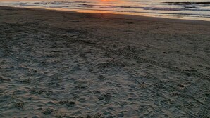 A beach at sunset with visible footprints in the sand.