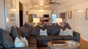 A living room with a sectional sofa, a coffee table, and a ceiling fan.