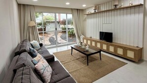 Ein modernes Wohnzimmer mit einem großen Ecksofa, einem Couchtisch und einem Fernseher auf einer Holzkommode.