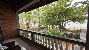 Ein überdachter Außenbereich mit Blick auf einen Garten und einen Strand.