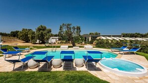 Ein Swimmingpool mit blauen Liegestühlen und einem Whirlpool, umgeben von einer Terrassenanlage.
