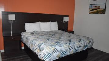 A bedroom with a bed, two bedside tables, a headboard, and a wall-mounted picture.