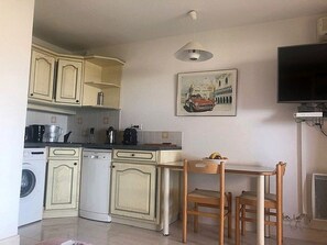 A compact kitchen with a washing machine, dishwasher, and a dining area with a table and chairs.