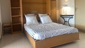 A bedroom with a wooden bed, a nightstand, and a built-in bookshelf. - Studio Cabin Exceptional Sea View South facing7 nights minimum. (Sainte-Maxime)