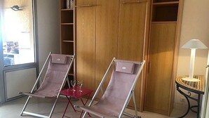A room with two reclining chairs, a small table with two wine glasses, and a wooden wardrobe. - Studio Cabin Exceptional Sea View South facing7 nights minimum. (Sainte-Maxime)
