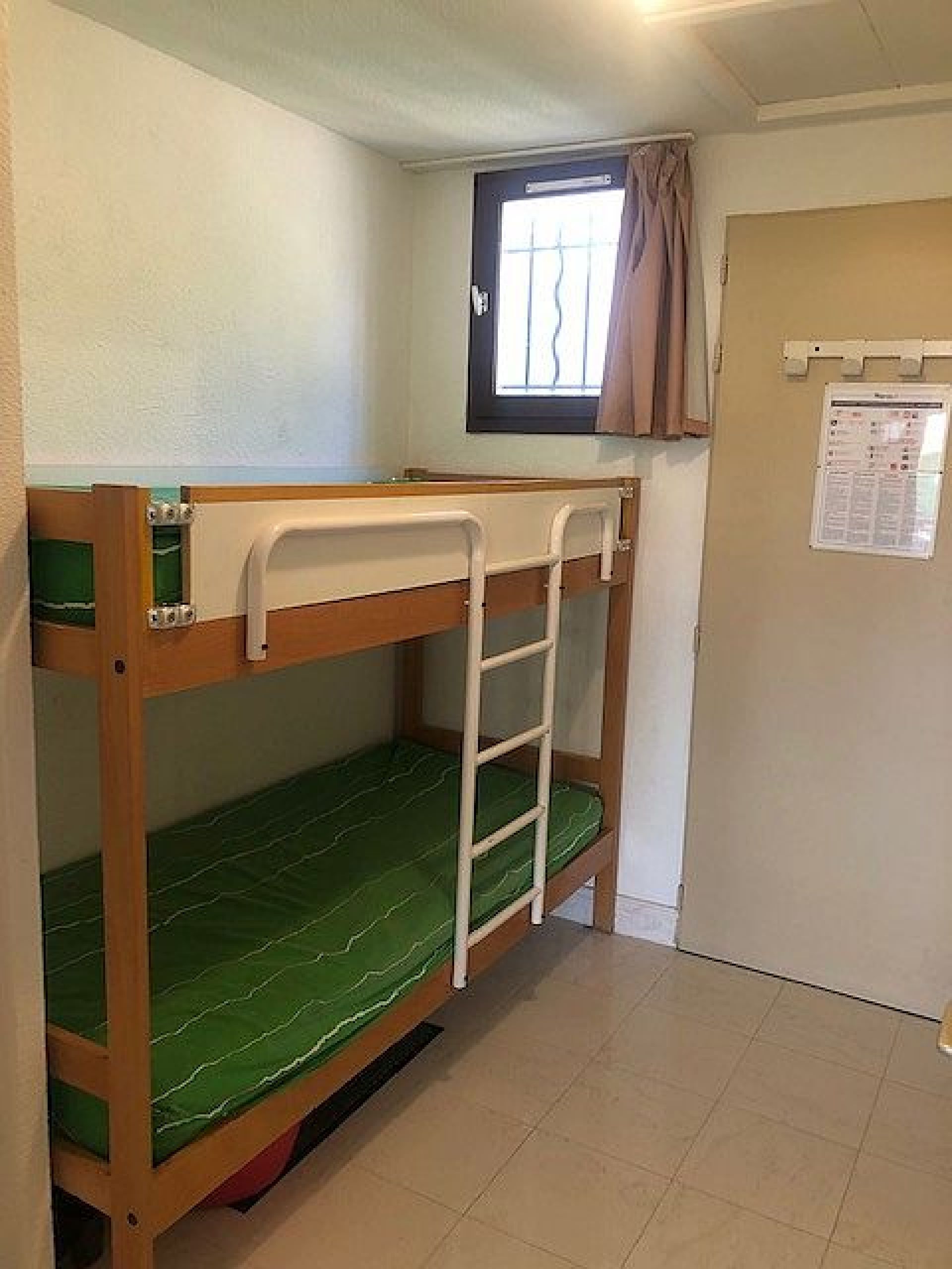 A bunk bed room with a window and a door.