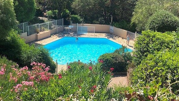 A rectangular swimming pool surrounded by lush greenery and a fence. - Studio Cabin Exceptional Sea View South facing7 nights minimum. (Sainte-Maxime)