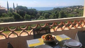 A balcony with a table set for dining, overlooking a scenic landscape with trees and distant buildings. - Studio Cabin Exceptional Sea View South facing7 nights minimum. (Sainte-Maxime)