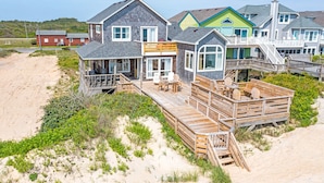 Une propriété située en bord de mer, comprenant plusieurs maisons reliées par des passerelles en bois, avec des espaces de détente en plein air et un accès direct à la plage.