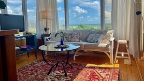 Un salon avec un canapé, une table basse, un téléviseur et une vue sur l’océan.
