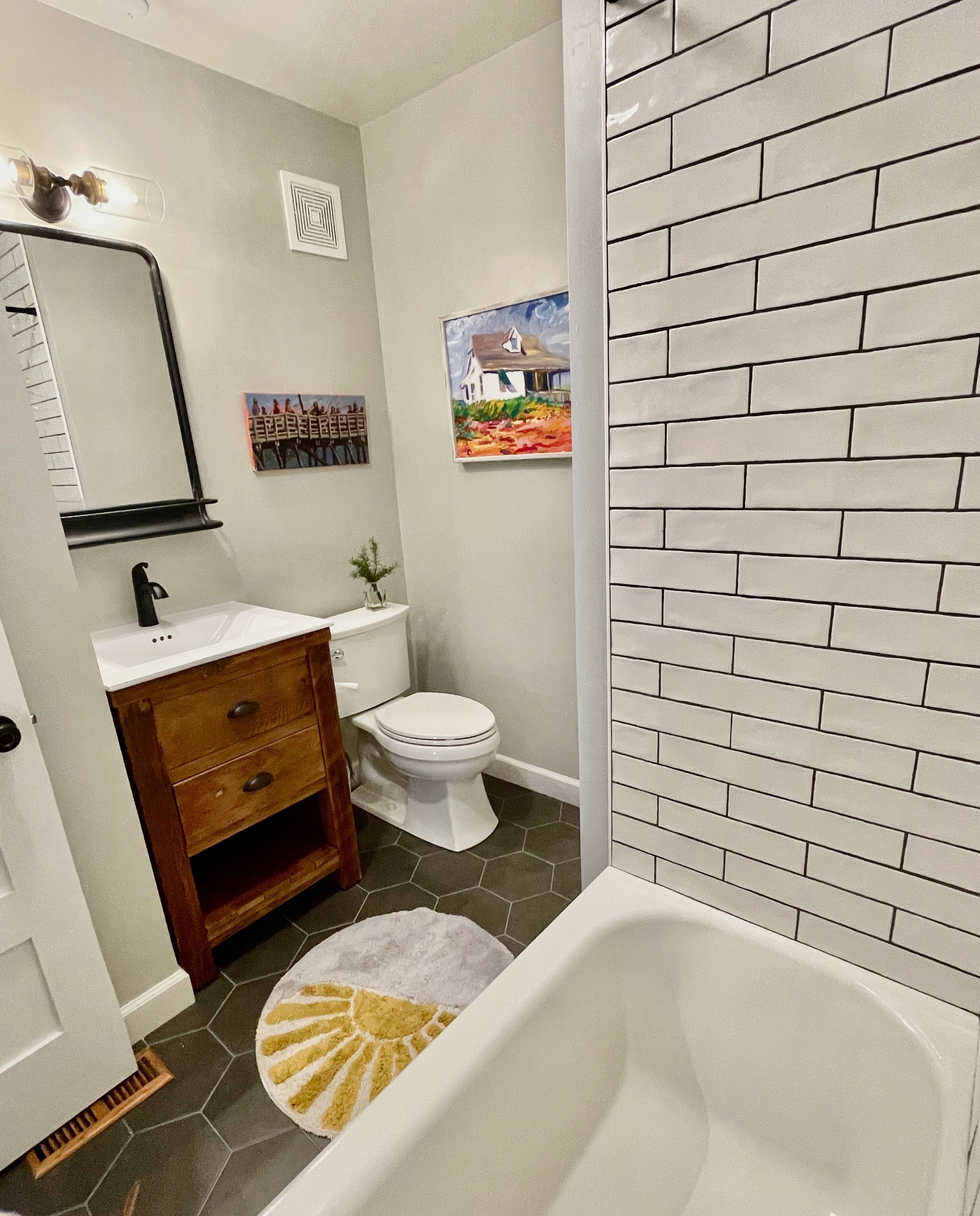 Une salle de bain avec un lavabo blanc, un meuble-lavabo en bois, des toilettes blanches et une baignoire.