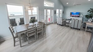 A spacious living area with a dining table, chairs, a TV, and a ceiling fan. - Waterfront Bay Views | Beautiful Private Pier (San Leon)