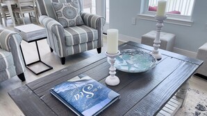 A modern living room with striped armchairs, a coffee table with a book and candles, and a view of the outdoors through a window. - Waterfront Bay Views | Beautiful Private Pier (San Leon)