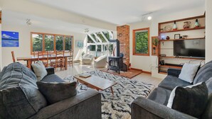 A spacious living room with a fireplace, a television, and a dining area with a view of the outdoors.
