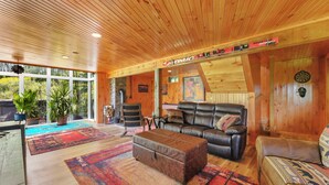 A spacious living room with wooden ceiling, leather sofas, and colorful rugs.