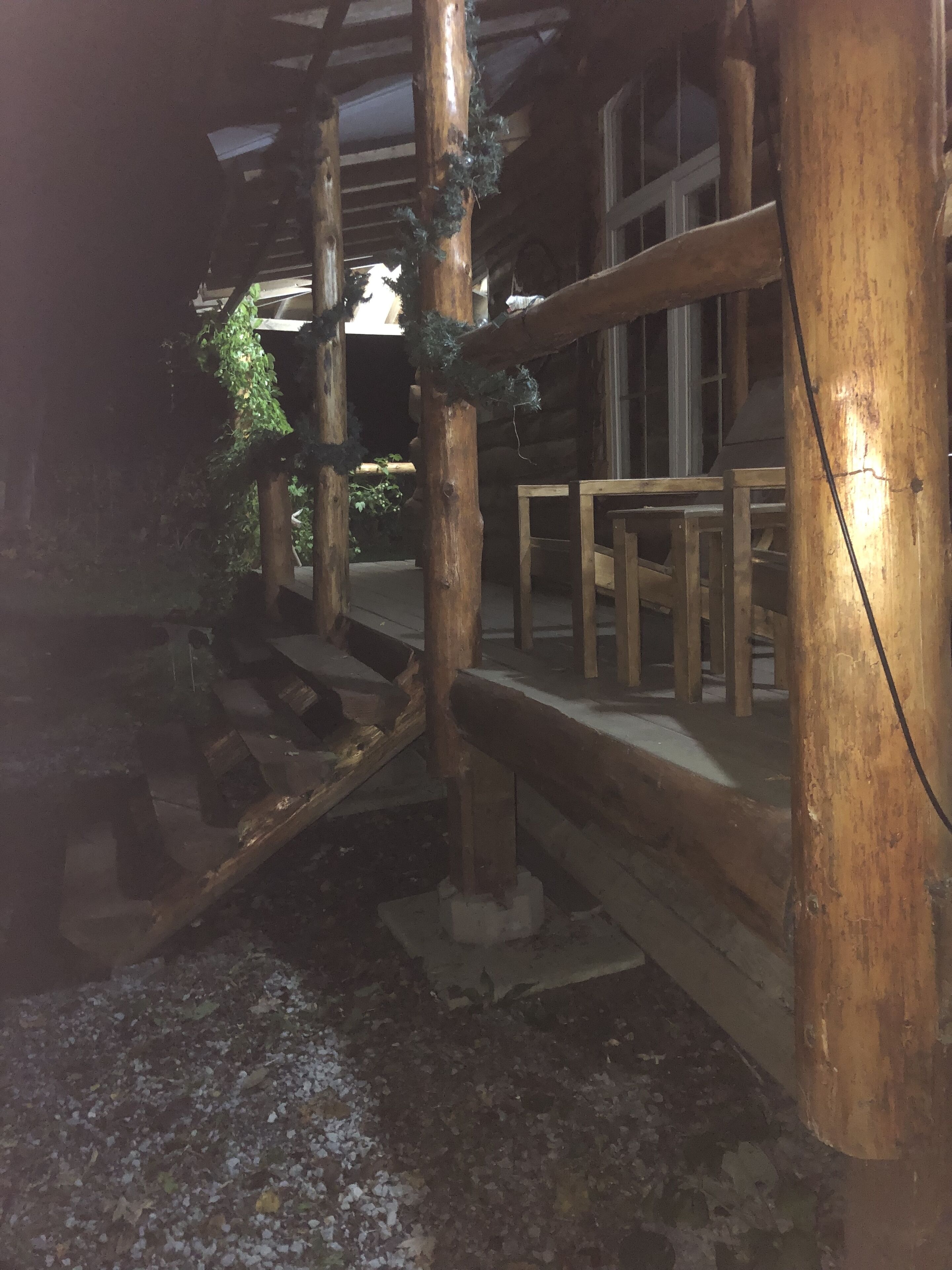 Une terrasse extérieure en bois, de style rustique, dotée d’une rambarde en bois et d’un banc.