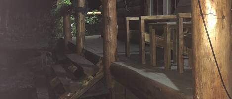 Une terrasse extérieure en bois, de style rustique, dotée d’une rambarde en bois et d’un banc.