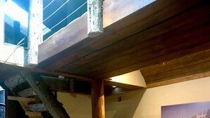 Un interior rústico con una escalera de madera, asientos de cuero y un cuadro enmarcados con un paisaje.