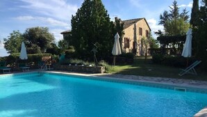 A clear blue swimming pool with lounge chairs and umbrellas, surrounded by a stone deck and greenery. - LAURO apartment kitchen, garden (Toscana)