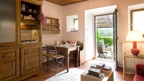 A cozy kitchen with wooden cabinets, a dining table with chairs, and a view through an open door to an outdoor area. - LAURO apartment kitchen, garden (Toscana)