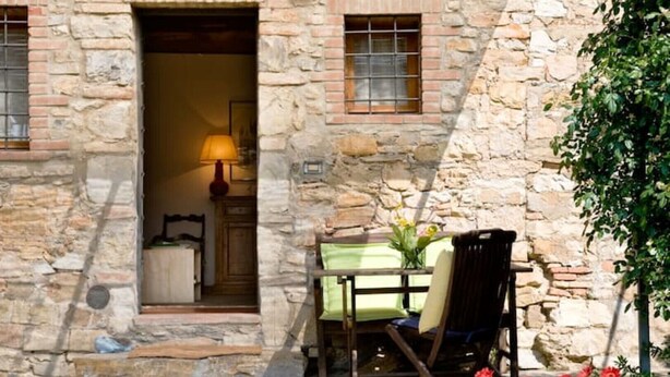 A stone building with a small outdoor seating area, a table, and chairs. - LAURO apartment kitchen, garden (Toscana)