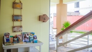 A room with a white table displaying books and a wooden sign with words "SAND," "BEACH," and "KELAX." - Bella Vida Hotel Punta Cana (Punta Cana)