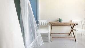 A room with a wooden table, two white chairs, a white curtain, and a small potted plant. - Bella Vida Hotel Punta Cana (Punta Cana)
