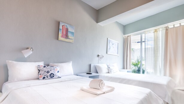 A hotel room with two beds, a nightstand, a lamp, and a window with curtains. - Bella Vida Hotel Punta Cana (Punta Cana)