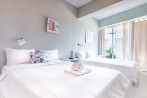 Una habitación de hotel con dos camas, una mesita de noche, una lámpara y una ventana con cortinas.