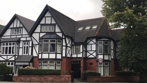 A Tudor-style house with a steeply pitched roof, multiple chimneys, and a prominent bay window. - Abbeyfield Guesthouse (Liverpool)